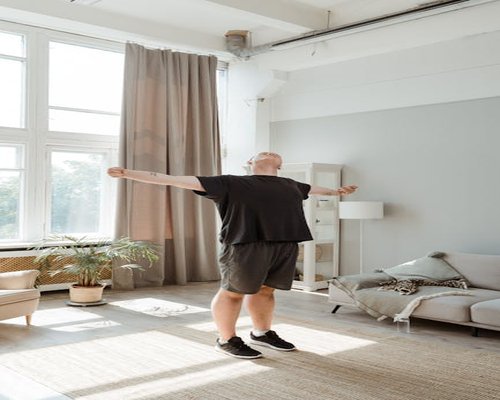 A relaxed person stretching near an open window with soft morning light filling the room