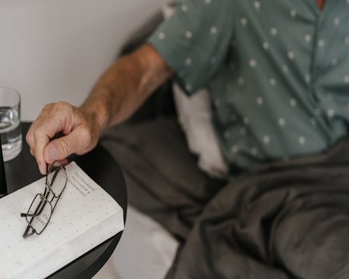 A dimly lit bedroom side table with a glass of water and a book signifying screen-free rest